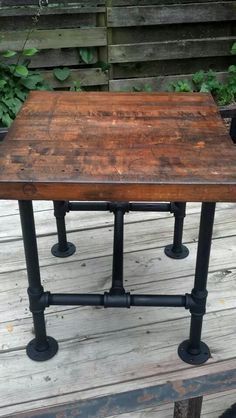 an old wooden table sitting on top of a porch next to some potted plants