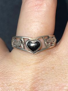 Beautiful sterling silver ring. Signed 925 and what appears to be CW. There is a black onyx heart in the center of the ring with very pretty cut out leaves surrounding. Please see photos for approximate measurements and further details. The ring is a size 7.75. Gift Black Sterling Silver Heart Ring, Vintage Silver Heart Ring For Gift, Vintage Silver Heart-cut Rings, Vintage Sterling Silver Heart Ring For Valentine's Day, Claire Core, Vintage Silver Hallmarked Heart Ring, Vintage Silver Ring, Promise Rings Vintage, 925 Ring