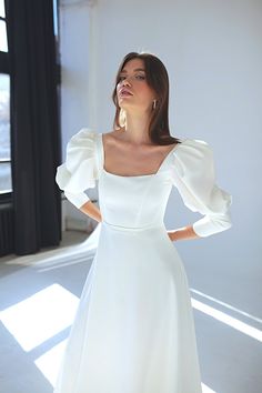 a woman in a white dress posing for the camera