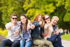 a group of young people sitting on top of a bench giving the thumbs up sign