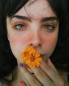 a woman holding a yellow flower in her mouth