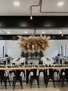 a long table set up with black chairs and tables covered in white linens, pamodia flowers and greenery