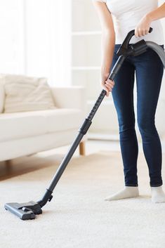 a woman using a vacuum to clean the carpet