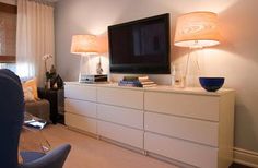 a living room with white furniture and a flat screen tv on top of a dresser