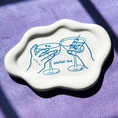 a blue and white plate with two drinks on it sitting on a purple tablecloth