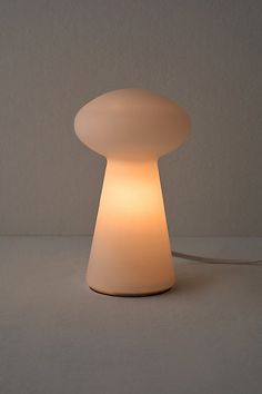 a white lamp sitting on top of a table next to a gray wall and floor