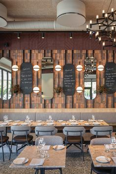 an empty restaurant with wooden tables and chalkboards on the wall behind them, along with place settings for people to eat