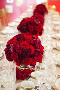 the table is set with red roses and gold place settings for an elegant dinner party