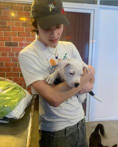 a young man holding a white dog in his arms