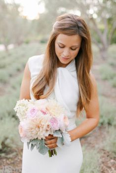 a woman in a white dress holding a bouquet of flowers