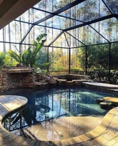 an indoor swimming pool in the middle of a patio area with glass walls and stone steps