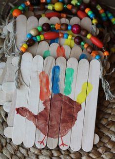 a wooden stick with a turkey painted on it sitting in a basket next to some beads