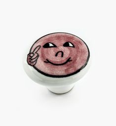 a white knob with a pink smiley face painted on it's front and side