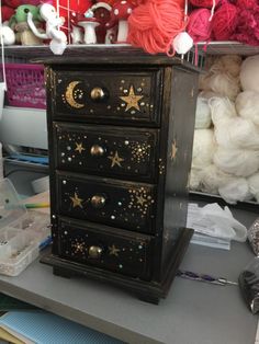 a black dresser with gold stars and moon decorations on it, next to some yarn