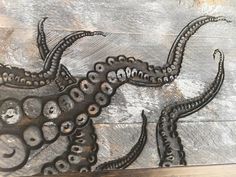 an octopus made out of metal on top of a wooden floor with holes in it