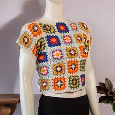 a crocheted top is displayed on a mannequin's head stand