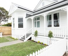 a white house with a picket fence in front of it and grass on the ground