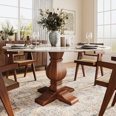 a dining room table with chairs and a vase filled with flowers on top of it