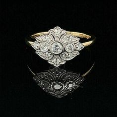 an antique diamond and gold ring on a black surface with reflection in the dark background