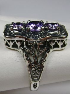 "Purple Amethyst Cubic Zirconia Description 3Stone Rectangle Design#60 MADE TO ORDER This is a lovely Edwardian reproduction 3 gemstone ring in solid sterling silver. The gorgeous filigree ring is set with 3 round cut purple amethyst CZ. The 2 smaller amethyst CZ's are 4.5mm in diameter; and the center amethyst CZ is 6mm in diameter. This filigree setting is a cast from an actual Antique design; notice the amazing etched accents... The ring sits 3/4th\" (19mm) NS on the finger. The quality of th Antique Silver Three Stone Jewelry, Unique Silver Three-stone Jewelry, Ornate Purple Amethyst Ring With Intricate Design, Unique Silver Three Stone Jewelry, Ornate Silver Amethyst Ring For Anniversary, Ornate Amethyst Ring For Anniversary, Antique Three Stone Jewelry Gift, Amethyst Three Stone Ring, Unique Silver Jewelry With Three Stones