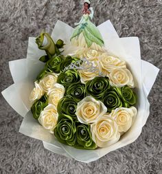 a bouquet of white roses and green leaves with a fairy tale brooch on top