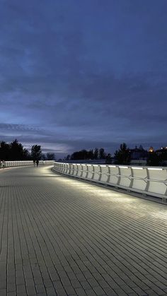 an empty walkway at night with people walking on it