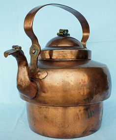 an antique copper tea kettle with a handle