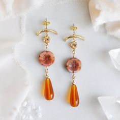 "These colorful bohemian earrings are created with wire wrapped orange glass teardrops and accented with pink flowers and gold sparkling topaz crystals. The retro 70s style dangle earrings are secured to light-weight textured gold plated arch earring posts. These lovely arch earrings are the perfect accessory for your next festival or to take center stage at your desert wedding. Your fun floral beaded boho bridal earrings will arrive suitably gift wrapped ready for gift giving. Measurements: The Orange Czech Glass Jewelry With Ear Wire, Orange Czech Glass Dangle Earrings, Orange Bohemian Flower Earrings For Gift, Bohemian Orange Flower Earrings For Gift, Vintage Orange Earrings With Czech Glass, Vintage Orange Dangle Earrings, Vintage Orange Czech Glass Earrings, Elegant Orange Czech Glass Jewelry, Orange Dangle Flower Earrings With Ear Wire