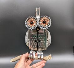 a hand holding a fork and an owl figurine