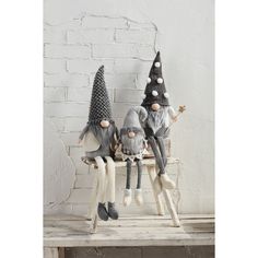 three gnome figurines sitting on top of a bench