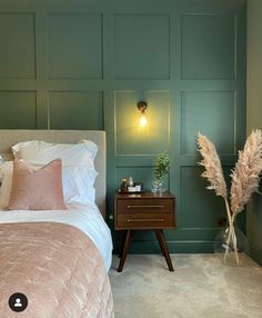 a bedroom with a bed, nightstand and lamp in front of the wall painted green