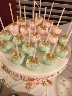 cake pops with gold sprinkles and pink frosting on a white plate