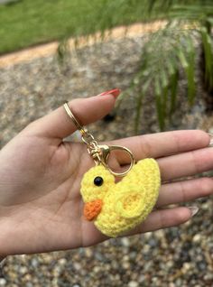 a hand holding a keychain with a small yellow duck on it