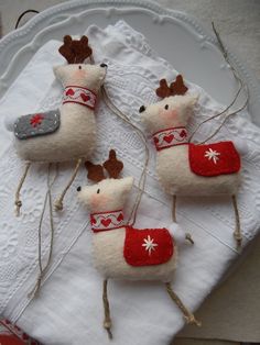 four small stuffed animals are sitting on a white plate with twine needles in the shape of reindeers