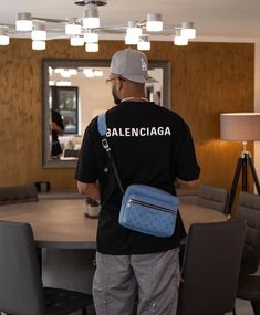 a man standing in front of a table with a blue bag on it's back