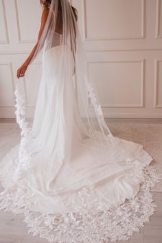 a woman in a wedding dress with a veil over her head and flowers on the floor