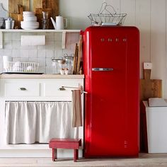 a red refrigerator sitting in the middle of a kitchen