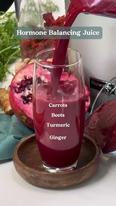 a glass filled with liquid sitting on top of a wooden tray next to some vegetables