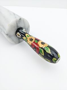 a marble toothbrush with floral designs on it's top and the handle is black