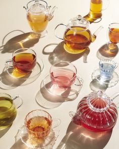 there are many different cups and saucers on the table with tea in each cup