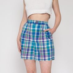 Vintage early 90s blue, green, and purple plaid shorts by Izod, with pleating at the front of the waist. Shown clipped on the model in the first two photos.  Measurements and Condition: Fits like: Labeled size 12, fits modern women's medium or up to a smaller size large Fabric: Cotton Brand: Izod Condition: Excellent Waist: 29" to 31.5" - stretches with elastic at back Hips: 45" - taken at the bottom of the zipper opening Rise: 13" Inseam: 6" Shown on a 5'8" model with measurements of 35"-26"-38", usually wears a size small to medium. See our FAQ for more info on sizing and condition ratings. Bermuda Bottoms With Built-in Shorts For Daywear, Casual Plaid Bottoms With Built-in Shorts, Short Leg Bottoms With Pockets For Daywear, Plaid Cotton Shorts For Daywear, Relaxed Fit Bermuda Bottoms For Daywear, Fitted High-waisted Shorts For Daywear, High Waist Plaid Cotton Bottoms, High Waist 90s Style Pants For Summer, 90s High Waist Summer Pants