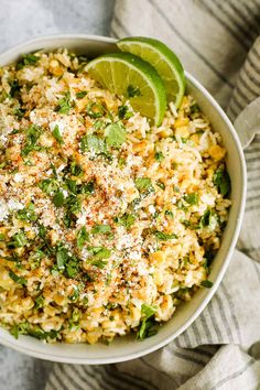 a white bowl filled with rice and garnished with cilantro, parsley and lime