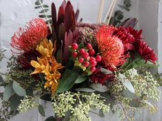 a vase filled with lots of different colored flowers and greenery next to a wall