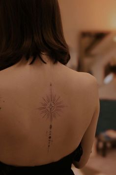 the back of a woman's shoulder with an arrow and sun tattoo on it