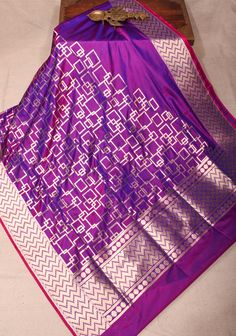 The Banarasi Katan Silk Saree in a stunning purple dual tone is a striking blend of elegance and artistry. Featuring an exquisite geometric jaal pattern, it showcases intricate patterns that reflect the rich heritage of Banarasi craftsmanship. The dual tone adds depth and sophistication, allowing the saree to radiate a captivating allure. Crafted from luxurious Katan silk, it drapes beautifully, making it ideal for special occasions and celebrations. This saree is a perfect choice for those seeking to make a bold yet refined statement with a touch of traditional charm SILK MARK CERTIFIED This saree is ready to wear with fall and pico done. Handmade silk tassels adorn the pallu and add more grace to it. An unstitched blouse fabric is included. *Note: There may be minor variations in the sha Luxury Purple Blouse With Zari Weaving, Luxury Purple Katan Silk Pre-draped Saree, Luxury Purple Katan Silk Traditional Wear, Luxury Silk Saree For Celebration, Luxury Katan Silk Unstitched Saree Suit, Luxury Katan Silk Unstitched Blouse, Luxury Unstitched Katan Silk Blouse, Luxury Unstitched Silk Mark Certified Saree, Luxury Katan Silk Saree Fabric