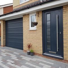 a brick house with a blue garage door and two planters on the side of it