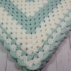 a crocheted blanket sitting on top of a white wooden floor covered in blue and white squares