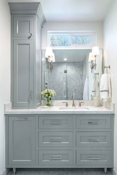 a large bathroom with two sinks and gray cabinets