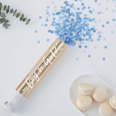 an open lip balm bottle next to some blue sprinkles on a white surface