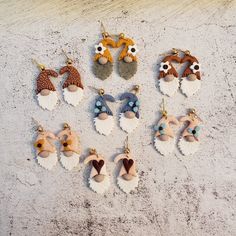 six pairs of earrings with animal heads on them sitting in the sand next to each other